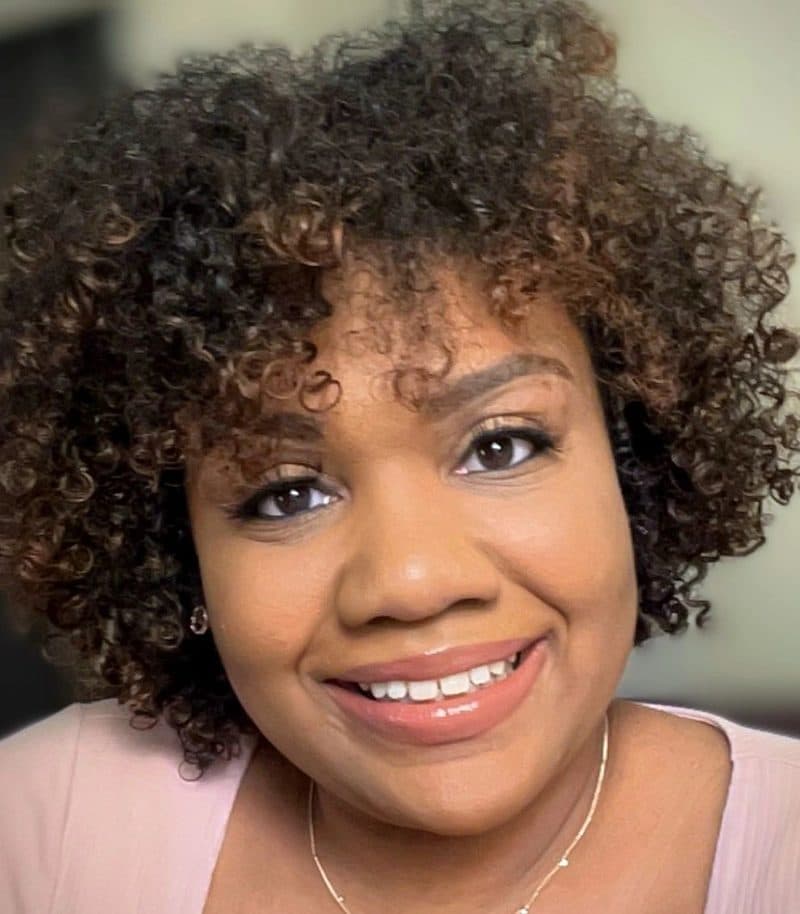 Portrait of Sydney Henderson smiling, in a pale pink top against a neutral background.